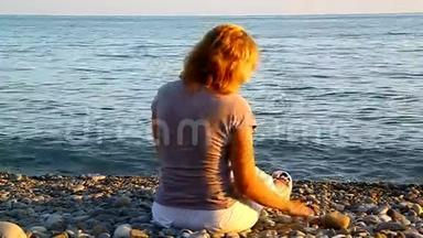 一个女人坐在海边的沙滩上<strong>扔石头</strong>